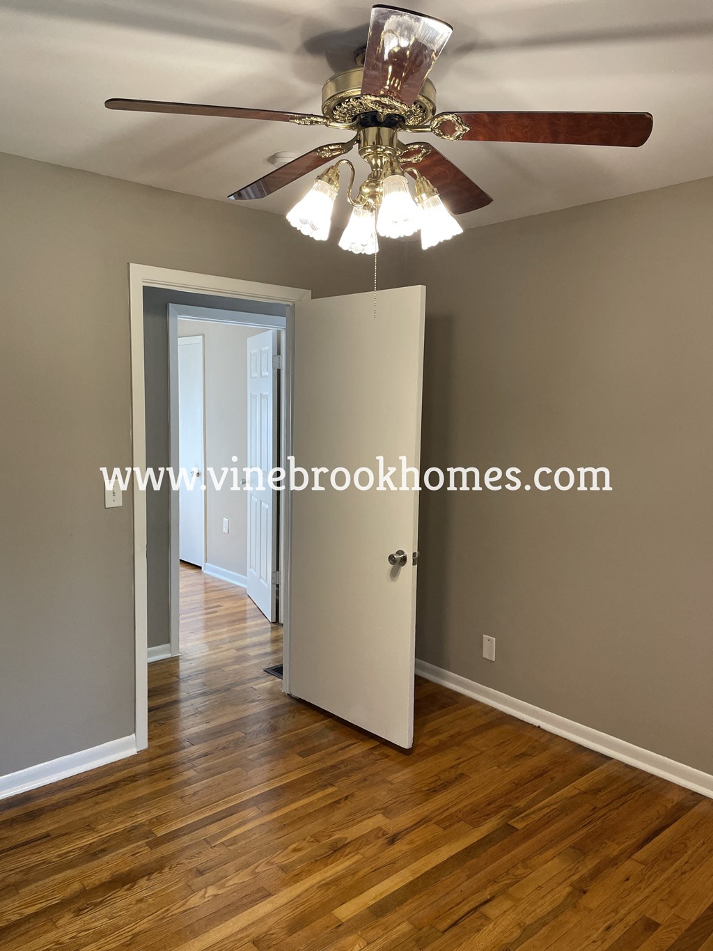 a bedroom door is open to a hallway with a ceiling fan