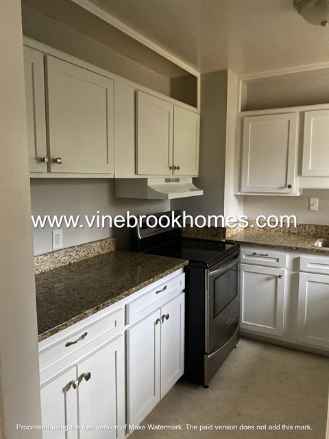 A kitchen with white cabinets and a granite countertop.