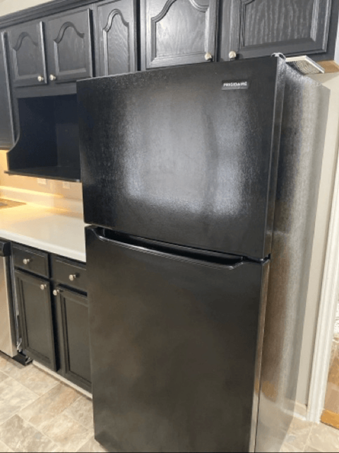 a stainless steel refrigerator in a kitchen with black cabinets