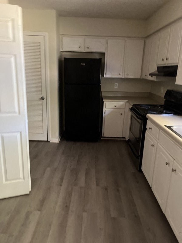 a kitchen with white cabinets and a black refrigerator