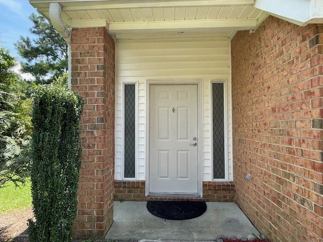 A white door is on the right side of a brick wall.