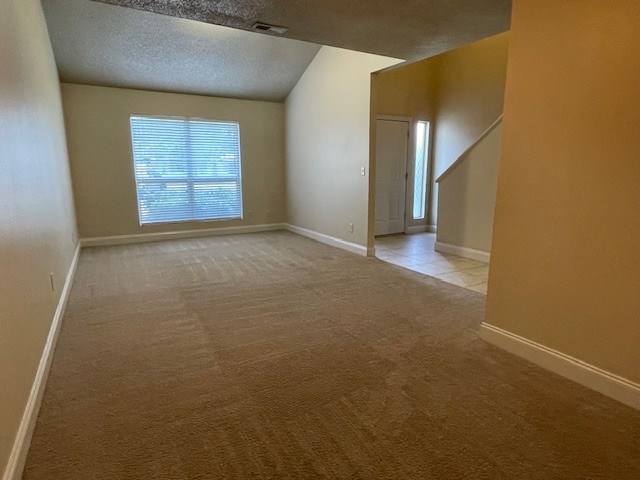 A room with a carpeted floor and a window with blinds.