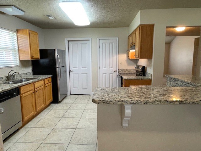 A kitchen with a black refrigerator and wooden cabinets.