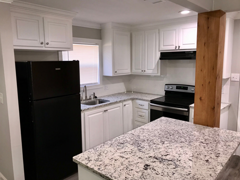 A kitchen with granite countertops and white cabinets.