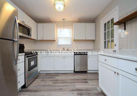 A kitchen with white cabinets and a stainless steel refrigerator.