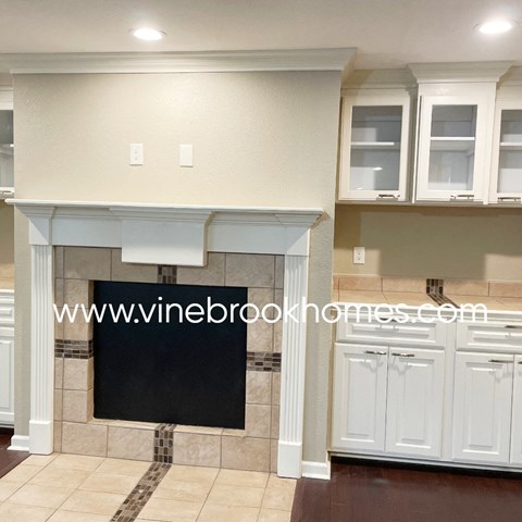 a kitchen with a fireplace and white cabinets