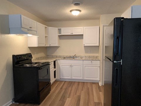 a kitchen with white cabinets and a black refrigerator
