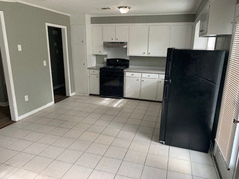 A kitchen with white cabinets and a black refrigerator.