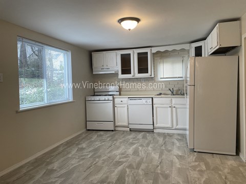 a kitchen with white cabinets and white appliances and a window