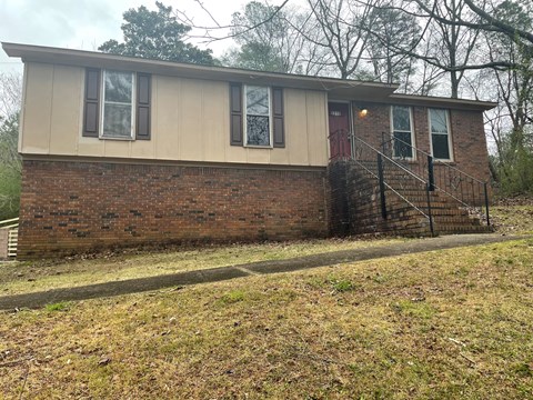 the front of a brick house with a porch and stairs