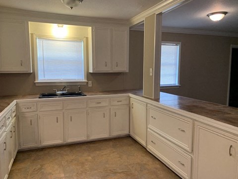 A kitchen with white cabinets and a tiled floor.