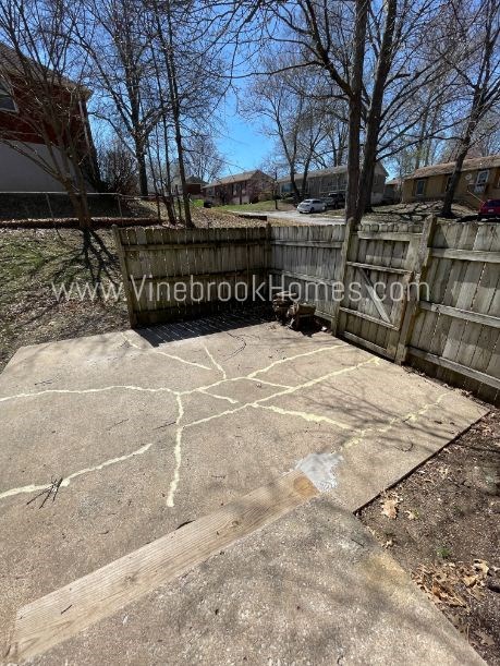 a backyard with a wooden fence and a concrete patio