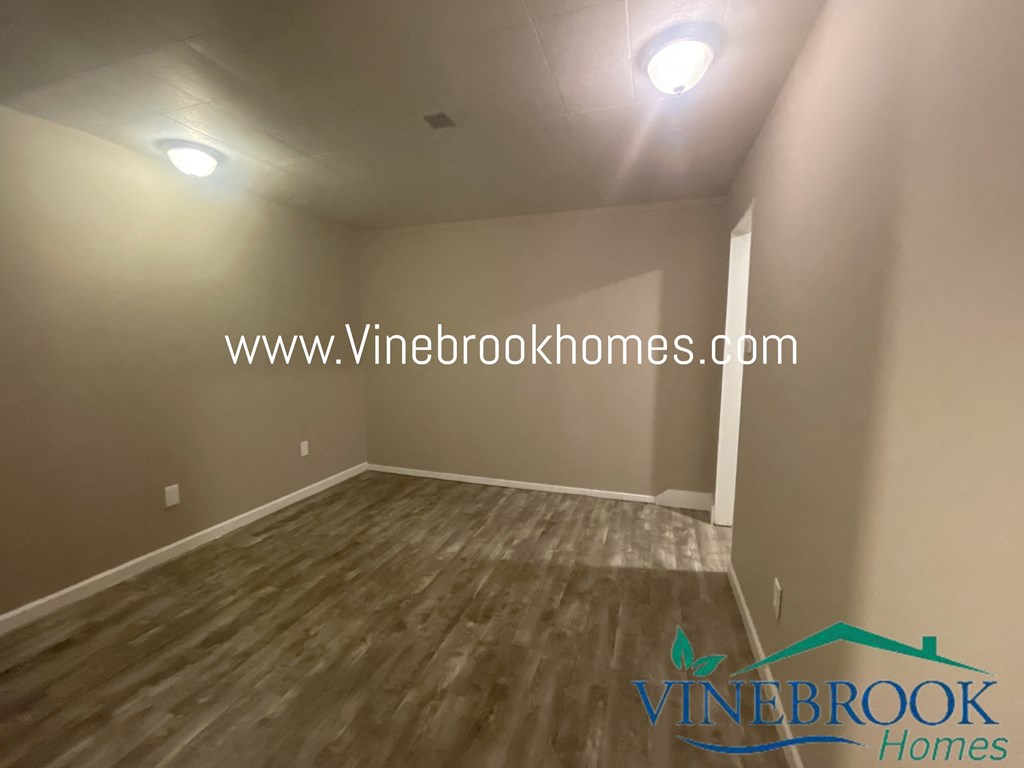 a bedroom with hardwood flooring and white walls and a window