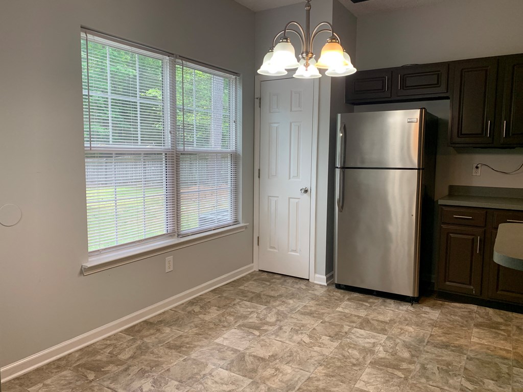 an empty kitchen with a refrigerator and a window