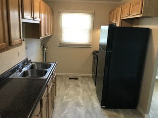 A black refrigerator in a kitchen with wooden cabinets.