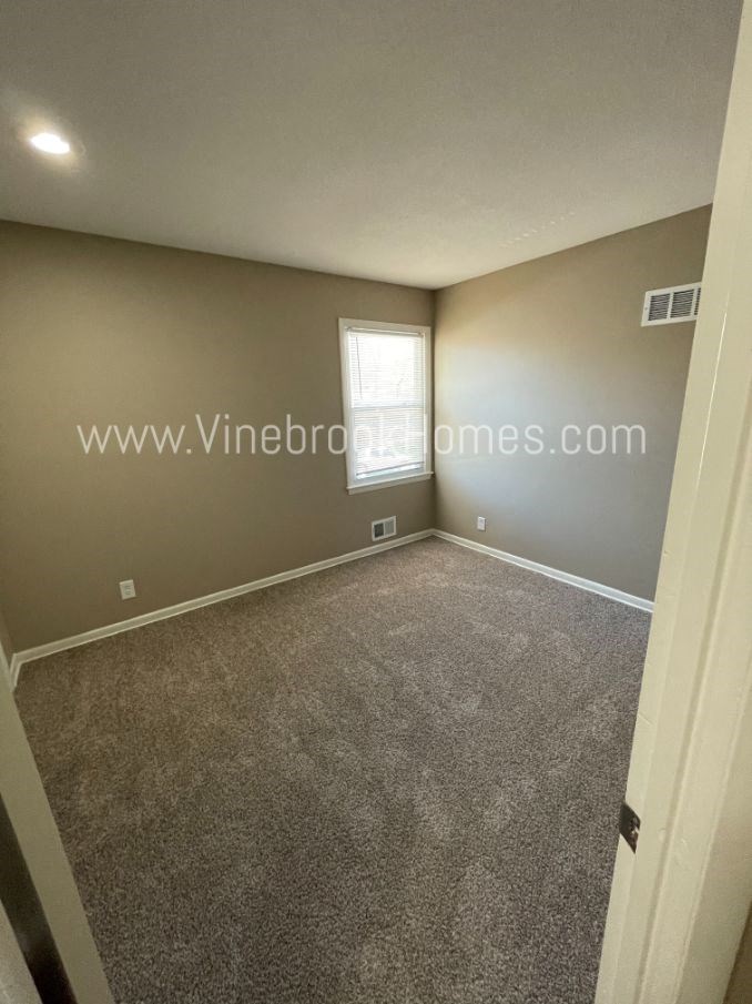 an empty living room with carpet and a window