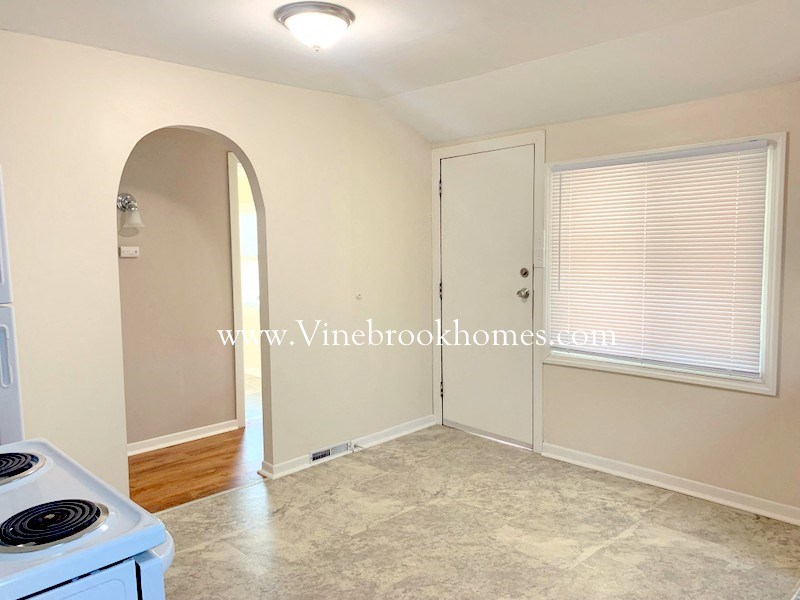 an empty kitchen with an arched door and a door way to a closet