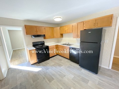 A kitchen with black appliances and wooden cabinets.
