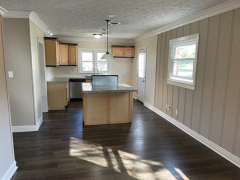 A kitchen with wooden floors and cabinets is shown.