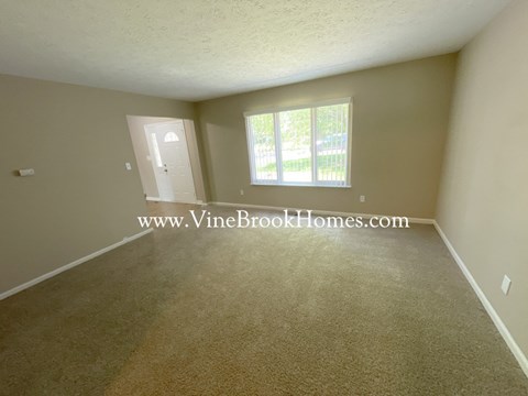 a small living room with carpet and a window