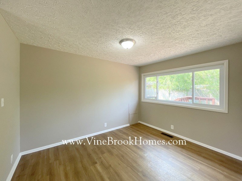 an empty living room with a large window and wood floors