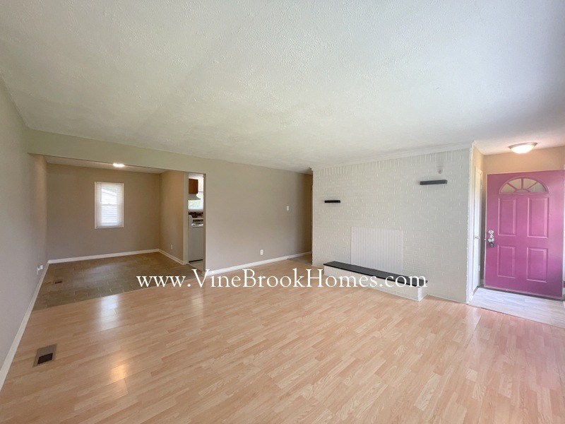 an empty living room with a pink door and wood floors