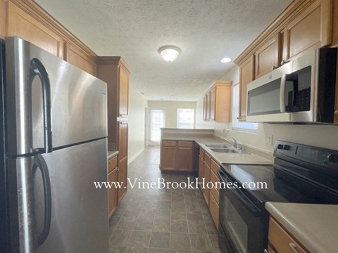 A kitchen with a refrigerator, microwave, and oven.