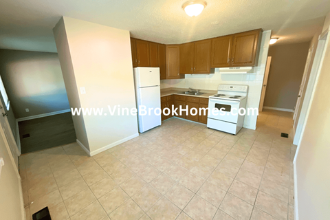 A kitchen with a white fridge and stove top oven.