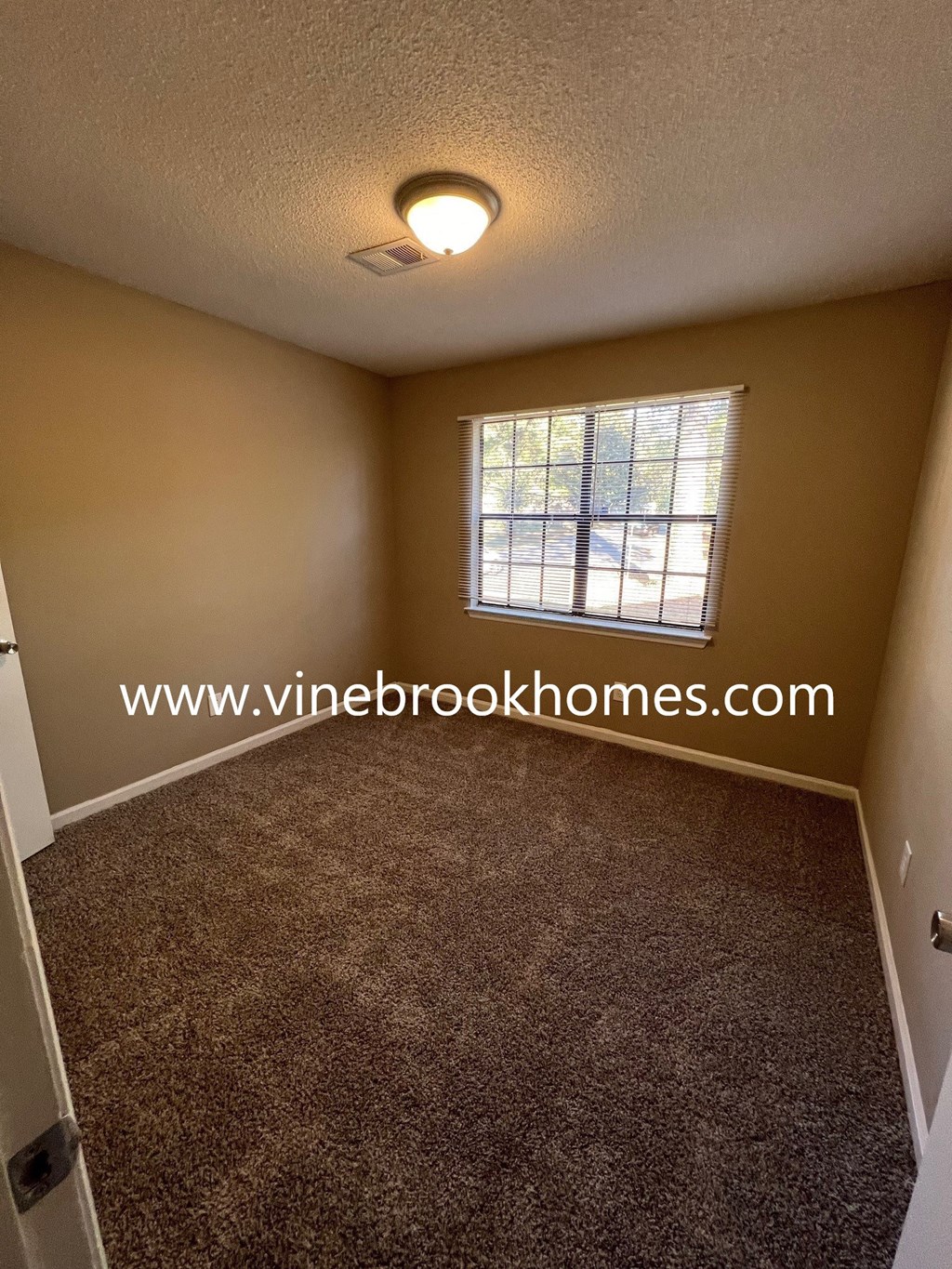 a small room with a window and a carpeted floor