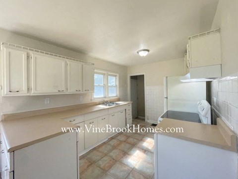 a kitchen with white cabinets and a sink and a refrigerator