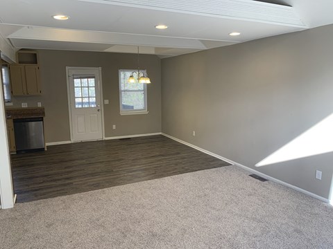 A spacious room with a kitchen area to the left and a door leading to another room.