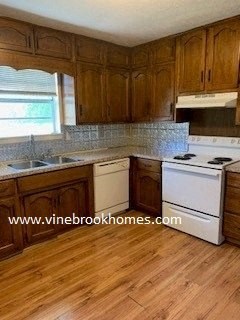 a kitchen with a stove and a sink and wooden floors