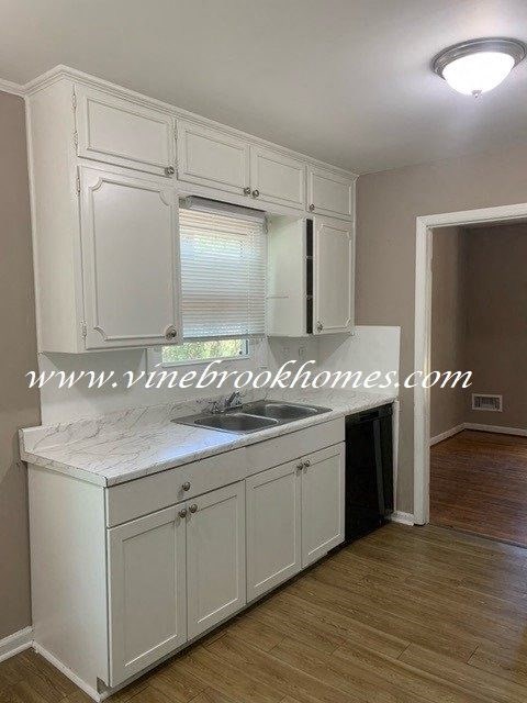 A kitchen with white cabinets and a marble countertop.