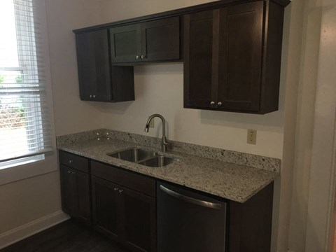 A kitchen with dark brown cabinets and granite countertops.