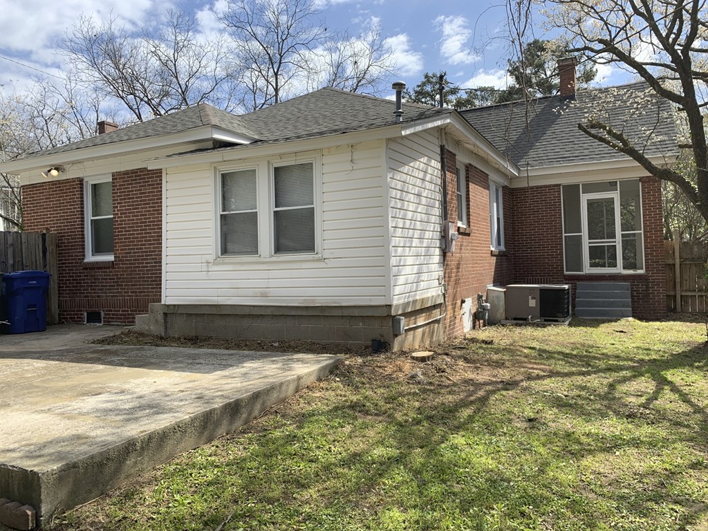 a white and brick house with a yard and a sidewalk
