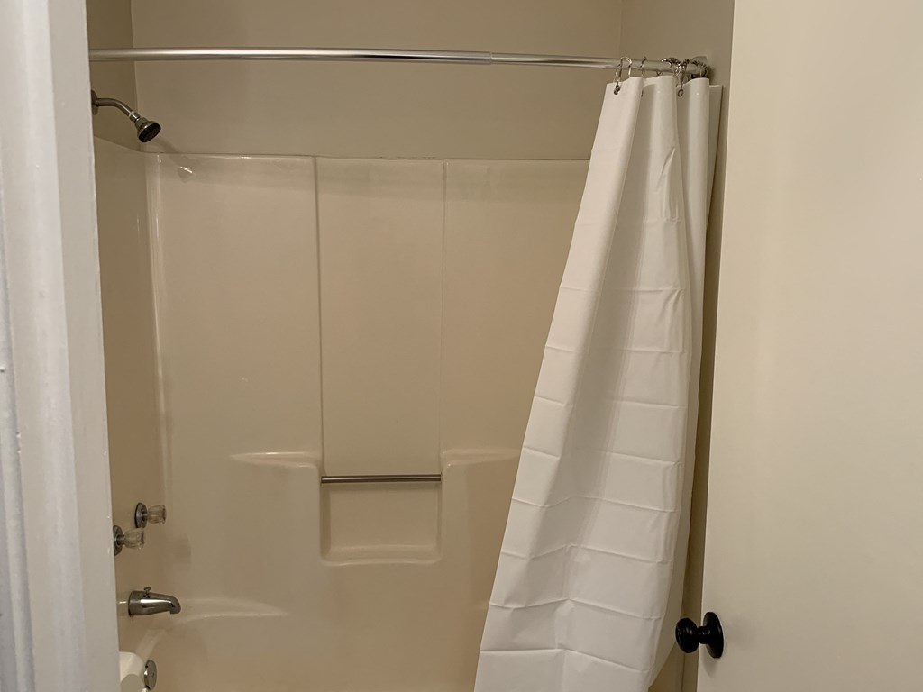 a bathroom with a shower and a white shower curtain