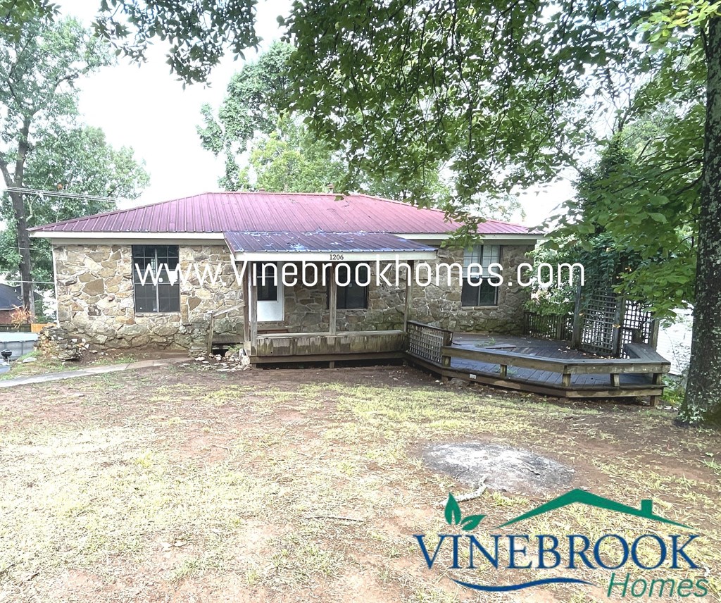 a stone house with a porch and a bench in a yard