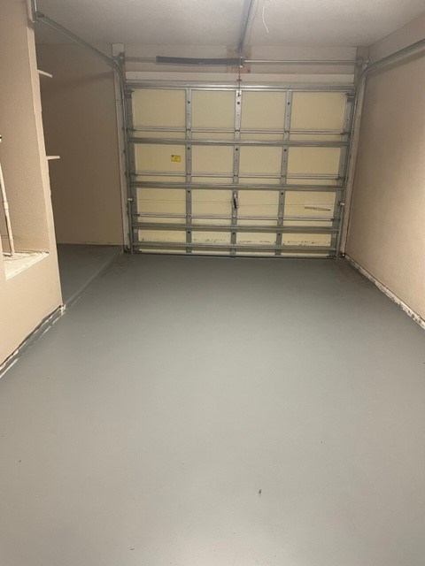 A large, empty garage with a metal shelving unit.