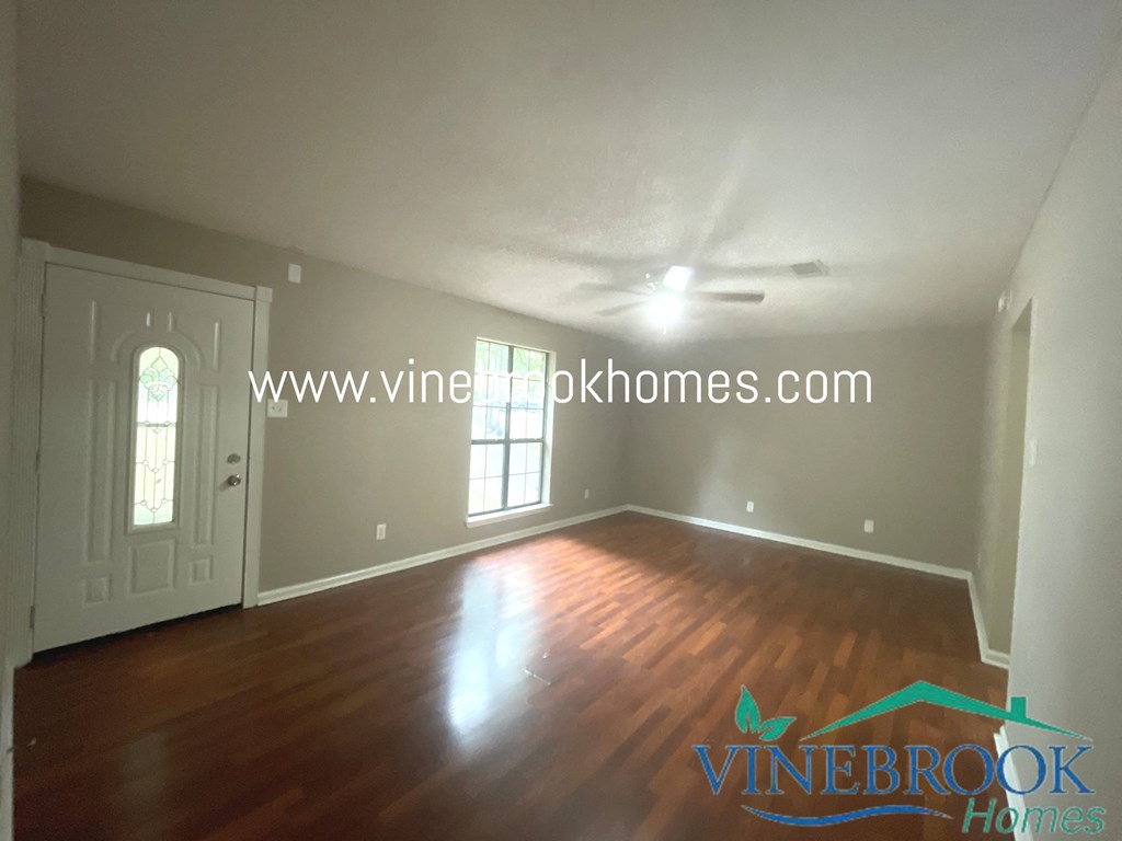 an empty living room with a hard wood floor and a white door