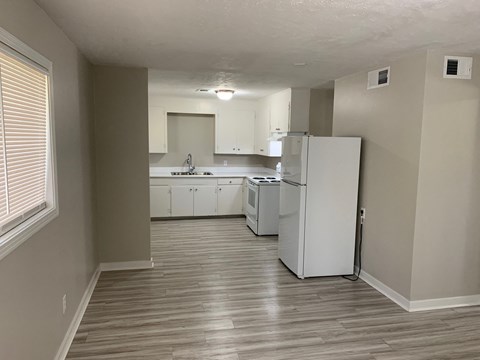 A kitchen with white appliances and wooden floors.