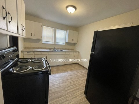 a kitchen with white cabinets and a black stove and refrigerator