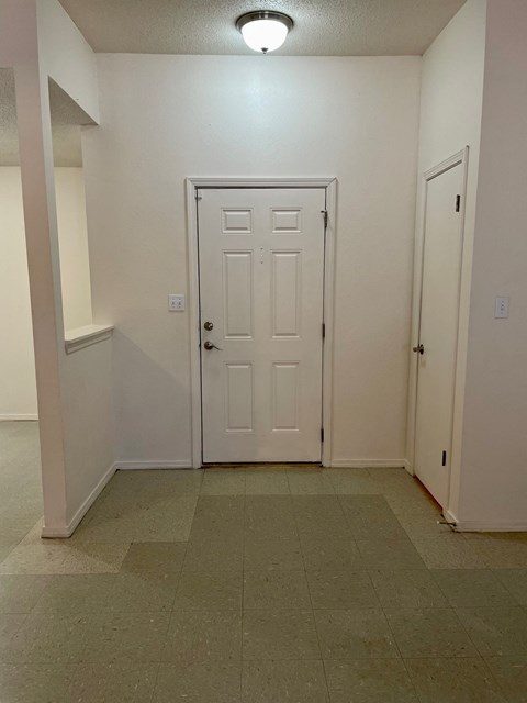 a room with a white door and a hallway with two doors