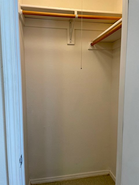 an empty closet with a pipe hanging from the ceiling