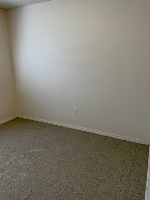 an empty room with a tiled floor and a white wall