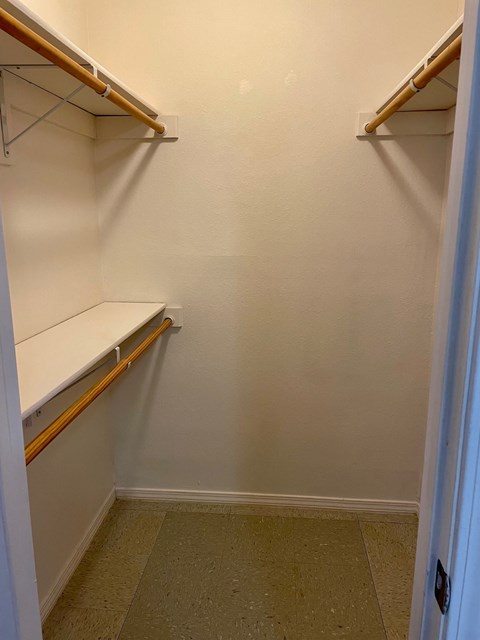 a walk in closet with empty shelves and a door