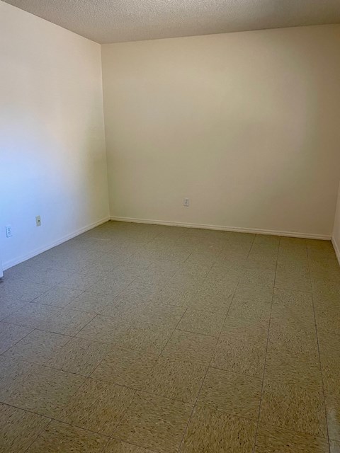 an empty living room with tiled floors and white walls