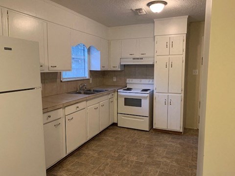 A kitchen with white cabinets and appliances.
