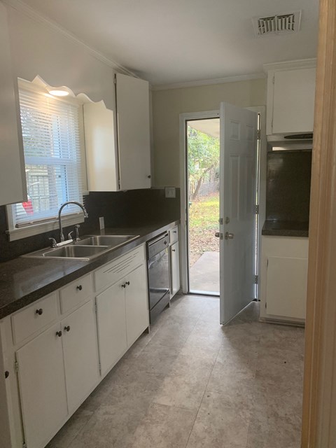 A kitchen with white cabinets and a black counter top.