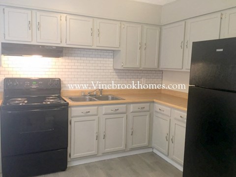 A kitchen with black appliances and white cabinets.