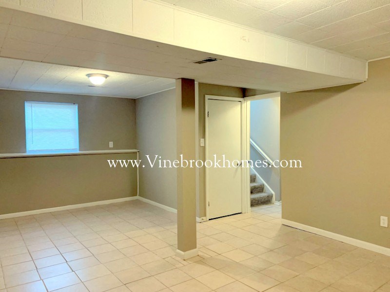 an empty living room with a staircase and a white tile floor